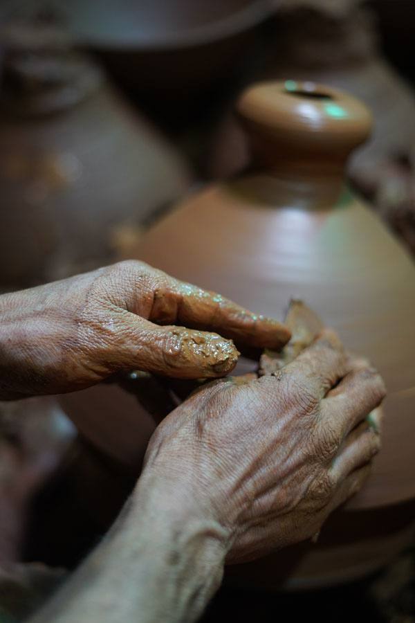 Artisan hands shaping a terracotta vessel on the wheel